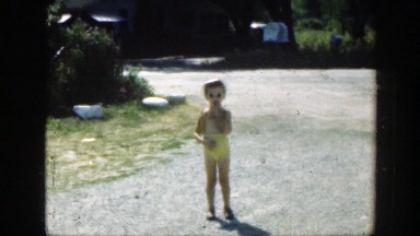 1947: little girl enjoying a great, summer day with her swim trunks on.