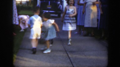 1949: some kids playing around in the driveway while their parents watch