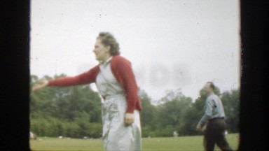 1949: a man and woman pick up and toss objects in a grassy field on a windy day