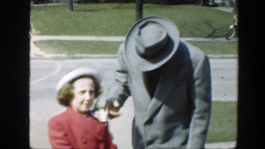 1949: a man and a little girl wearing hats, outside talking on the street