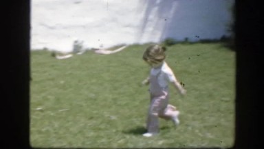 1945: A Cute Little Girl in Pink Overalls Running Through the Yard