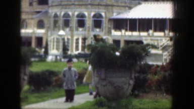 1949: two young children and an adult walking up a path lined with bushes