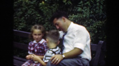 1948: father and children enjoying the day together, sitting on a park bench.