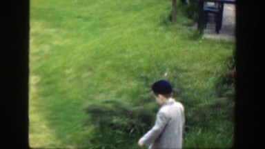 1949: happy little boy runs to the edge of the man made pond at the park.