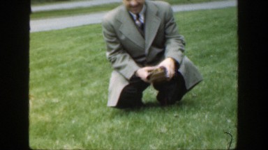 1949: Man Knelt in Grass Holding Book, Cincinnati Ohio
