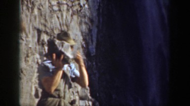 1937: A Man Wearing a Hat Throwing a Large Rock into a Waterfall California