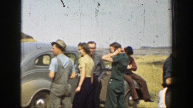 1937: Group of People Standing Around a Car in the Desert Talking and Smoking