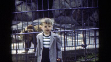 1949: A Nervous Little Boy in an Overcoat Poses in Front of a Caged Bear