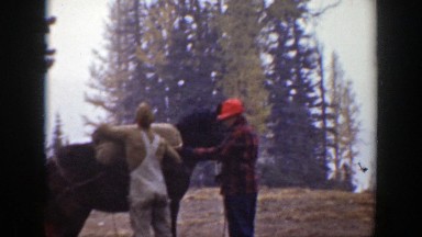 1938: Two Men Loading a Bundle onto a Horse's Back During Light Snow