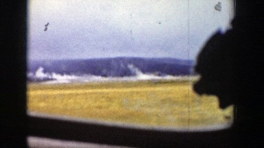 1939: ride through a grassy field with snowy mountains in the background.