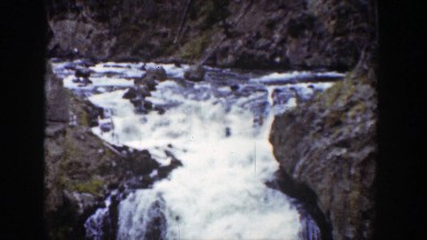 1939: Waterfall Flowing Into Large River with People in Wyoming