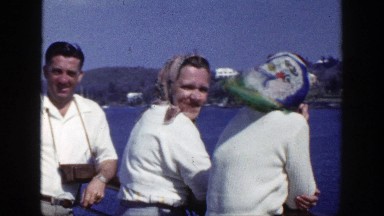 1948: Man and Two Women Stand at Railing Watching Boat Races on New York Shoreline