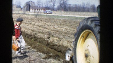 1954: a boy and his father walking behind a tractor in a field WISCONSIN DELLS