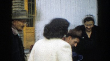 1957: a family is gathered outside of a building and two women greet each other