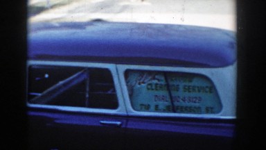 1954: a man stands beside his car, advertising a window cleaning service.