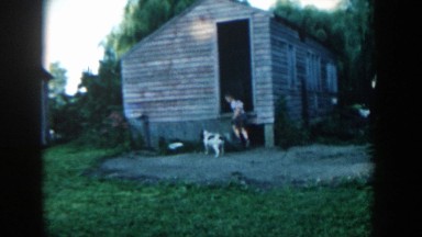 1957: little boy waving to the camera from inside the smokehouse. MICHIGAN