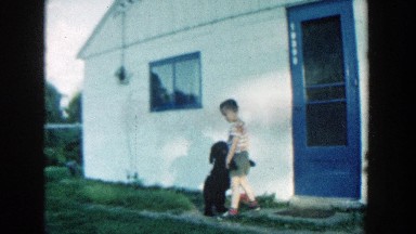 1957: boy holds dog outside home, enjoying the day MICHIGAN