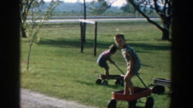 1958: children playing outside in their little red wagons. MICHIGAN
