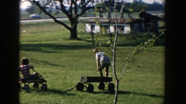 1958: Three Boys Wearing T-Shirts and Shorts Playing on Wagons in a Yard