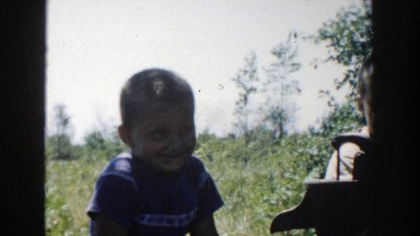1958: a smart boy sitting in the shade smiling and another one drinking water