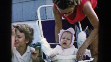 1958: a baby wearing a bonnet at a party sitting in the stroller MICHIGAN