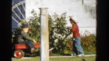1958: A Child Pulling Another Child on a Red Wagon in Michigan