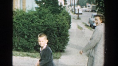 1964: child and woman walking on a sidewalk waving to camera WISCONSIN