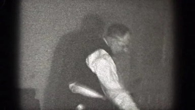 1939: man in a room walking around to see another man that has fallen CHELAN