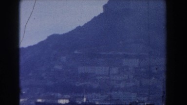1959: Landscape View of a Town Near a Mountain and a Large Body of Water