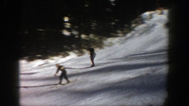 1961: skiers ski down a snow covered slope lined with evergreen trees ASPEN