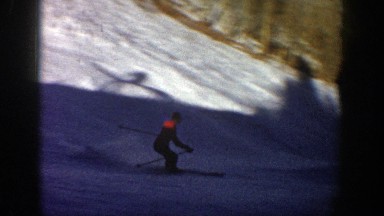 1961: a man is skiing down a mountain slope, doing a slalom from right to left