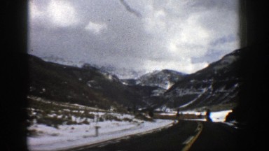 1961: old footage of a person or family driving into a mountainous region during