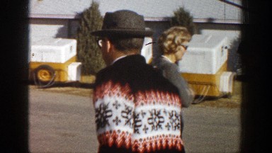 1961: a couple wearing sunglasses and smiling open a letter while standing in a