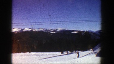 1961: a sunny day on a mountain, skiers in the background and a ski lift with