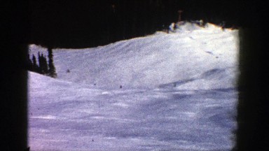 1961: four skiers are leisurely skiing downhill as seen from a stationary point