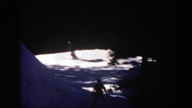 1961: two people ski down a snowy mountain slope among pine trees. ASPEN