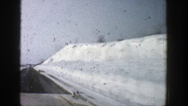1961: driving on blacktop with snow on the sides and adjacent mountainsides