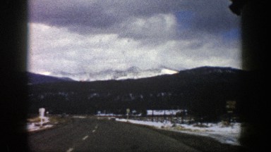 1961: driving on blacktop with snow on the sides and adjacent mountainsides