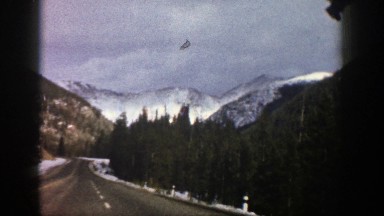 1961: driving on blacktop with snow on the sides and adjacent mountainsides