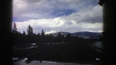 1961: driving on blacktop with snow on the sides and adjacent mountainsides