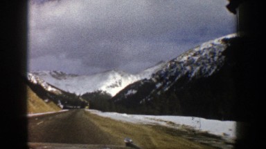 1961: driving on blacktop with snow on the sides and adjacent mountainsides