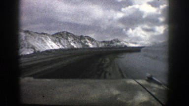 1961: driving on blacktop with snow on the sides and adjacent mountainsides