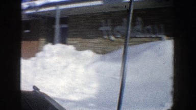 1961: long and high pile of plowed snow separates moving car from side of