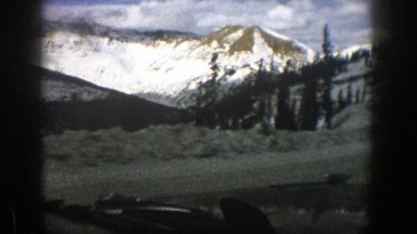1961: driving on a shadowy road overlooking a valley through a snowy mountain