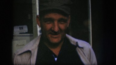 1958: middle aged man wears cap, talks, turns head, leans and lifts one side of