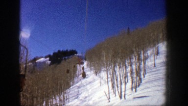 1961: View from Moving Ski Lift Heading Up Snowy Mountainside Between Dead Trees