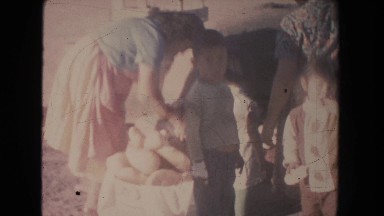 1951: two women baking bread stand by clay oven near fresh loaves while children