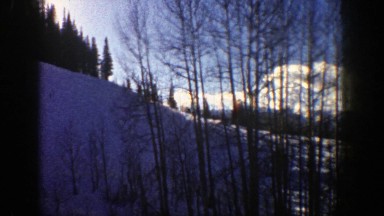 1961: driving through the snowy hills amongst the sunlit trees. ASPEN COLORADO
