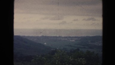 1961: old footage of a landscape with trees, mountain and a small city HAWAII