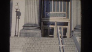 1960: nicely dressed older lady & young man walking up the stone steps of a